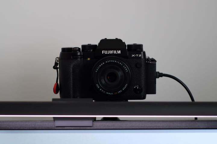 A Fujifilm X-T2 with 27mm f/2.8 mounted on top of a monitor, with a USB connected